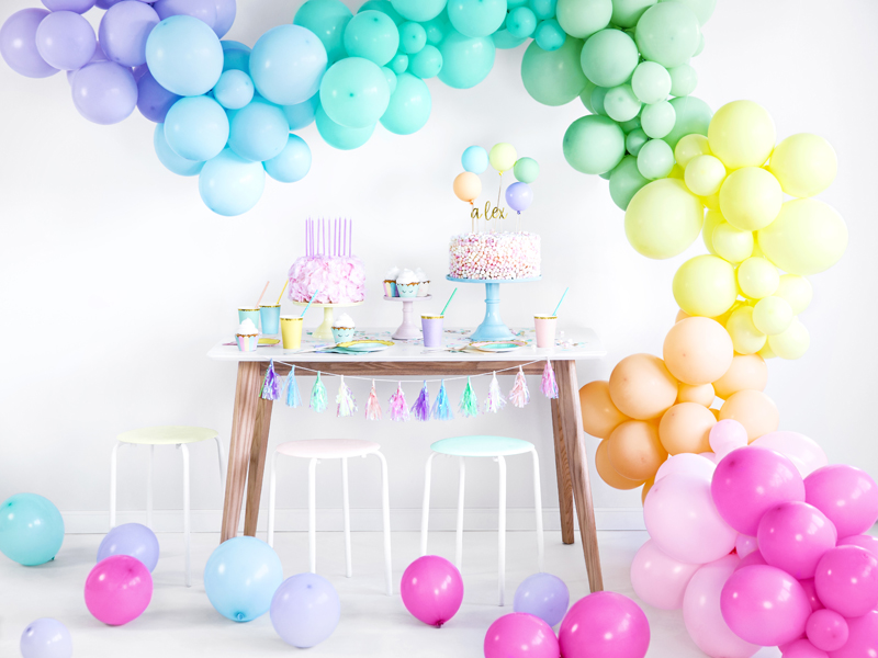 Decoração de festa com balões coloridos e mesa com bolo e copos pastel