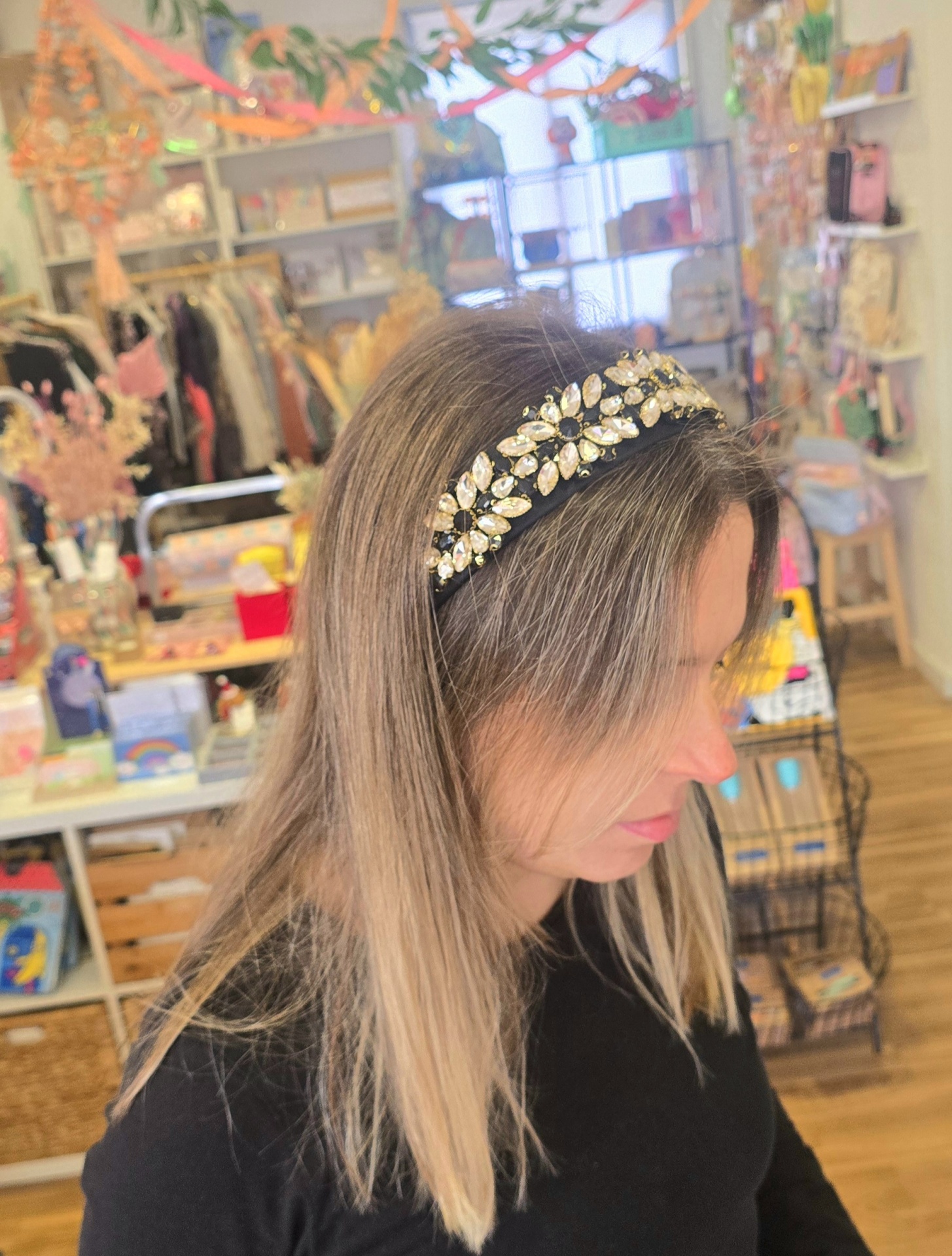 Diadema preta com brilhantes em forma de flores usada por mulher em loja