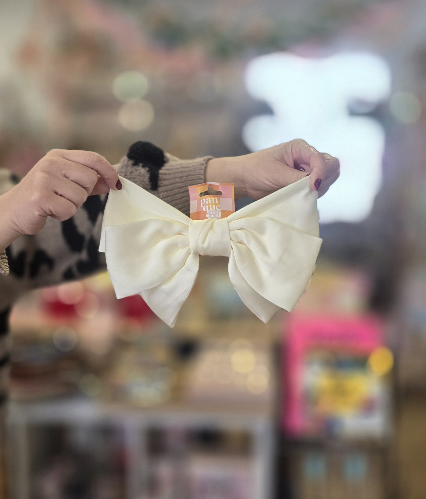 Laço branco de tecido acetinado com etiqueta panque ca segurado por mãos femininas