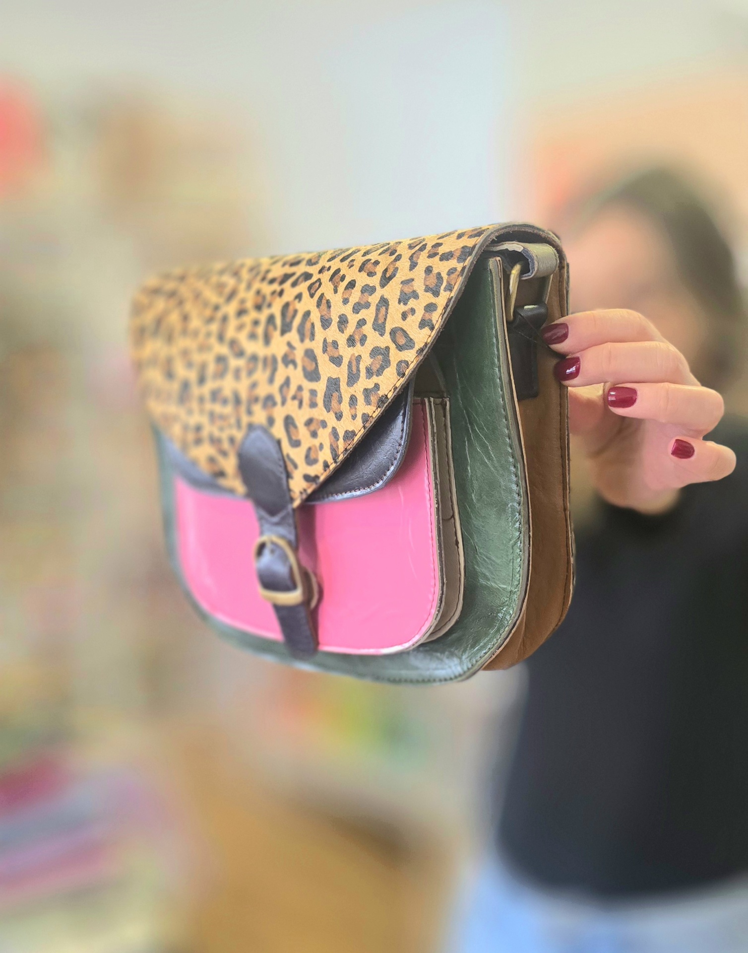 Mala em pele com padrão animal print, bolso frontal rosa e detalhes castanhos e verdes