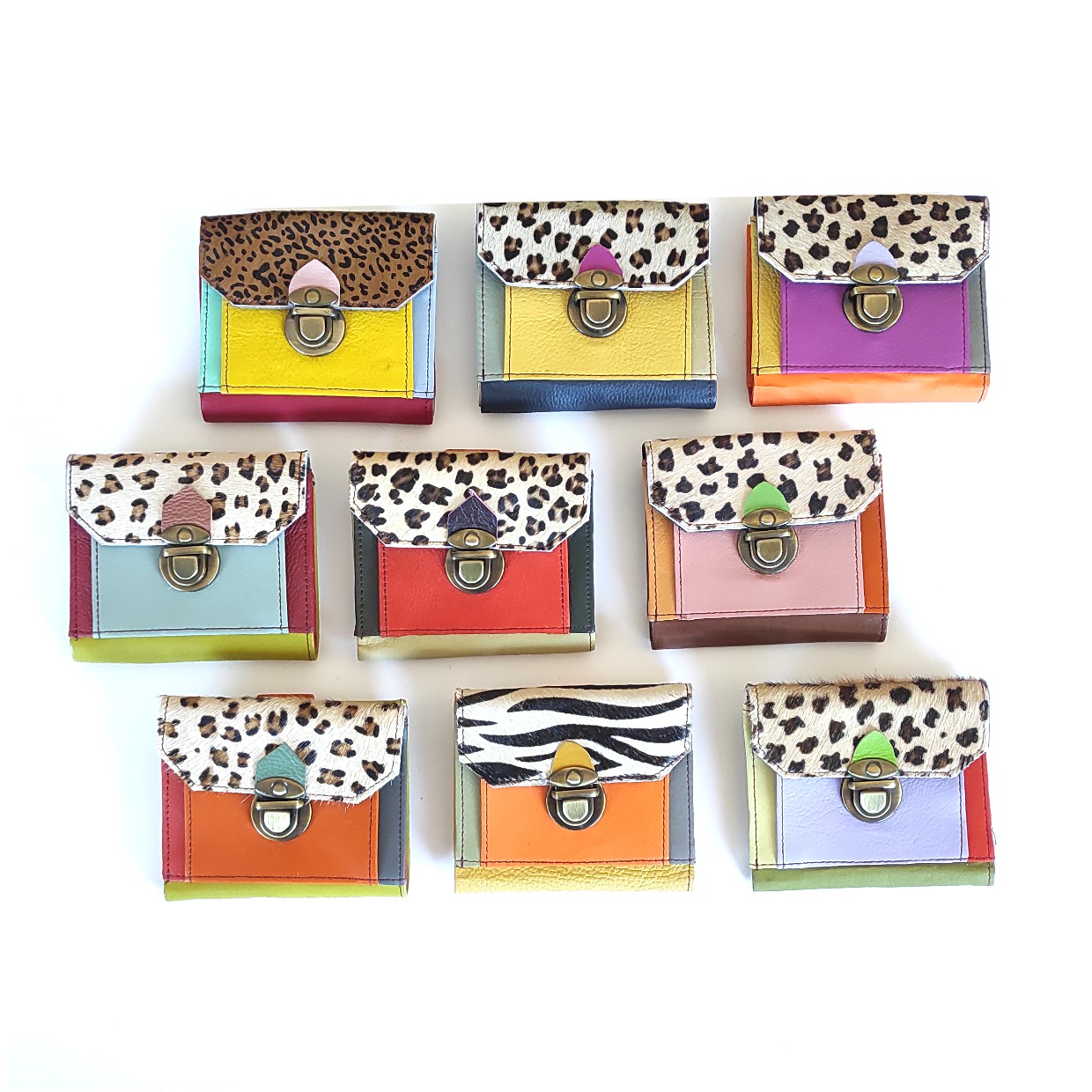 Oito carteiras coloridas com padrões animais e fechos metálicos sobre fundo branco