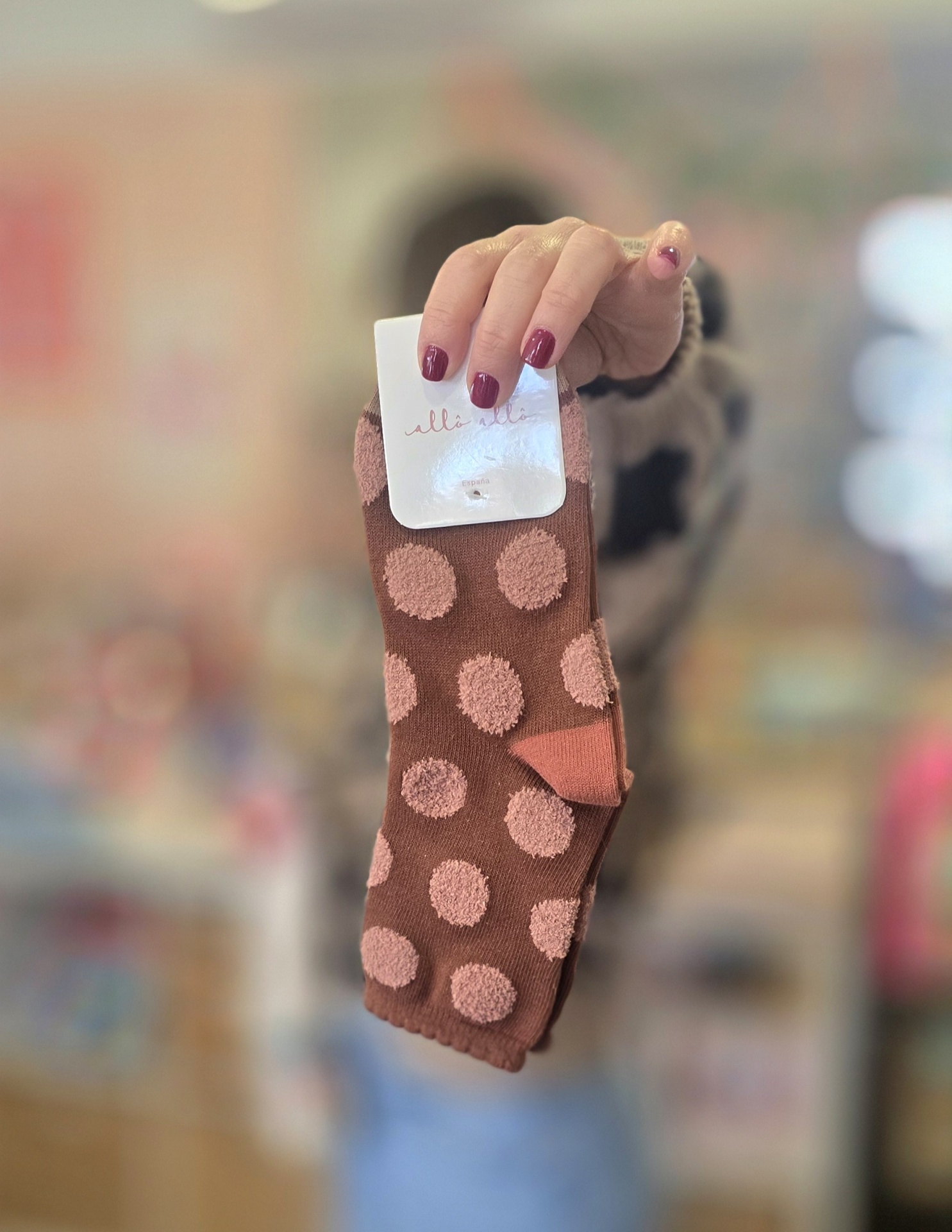Meias castanhas com bolinhas rosa e etiqueta branca às mãos