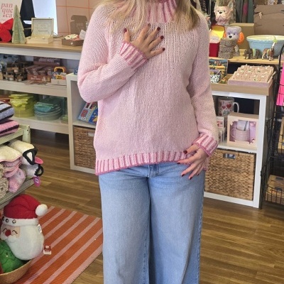 Mulher com camisola rosa de riscas e calças de ganga largas numa loja