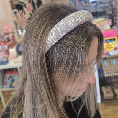 Faixa de cabelo espessa com pedras brilhantes prateadas usada numa mulher com cabelo loiro acinzentado