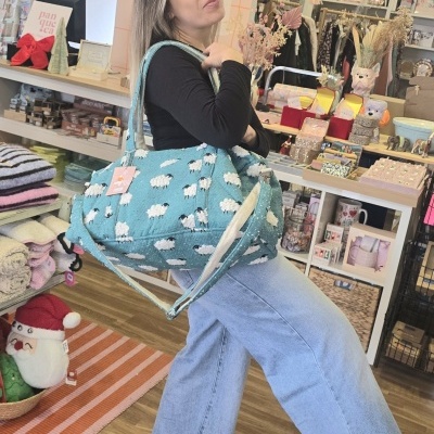 Mala azul com padrão de ovelhas em ambiente de loja colorida