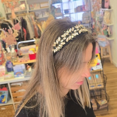 Diadema preta com brilhantes em forma de flores usada por mulher em loja