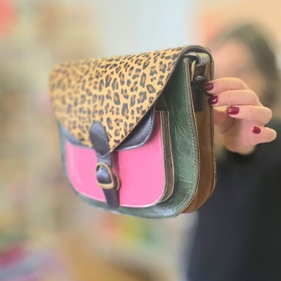 Mala em pele com padrão animal print, bolso frontal rosa e detalhes castanhos e verdes