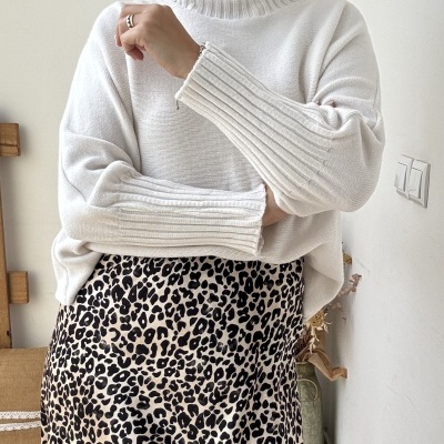 Mulher com camisola branca de gola alta e saia com padrão animal print