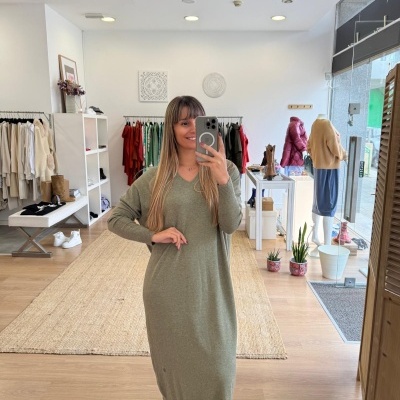 Mulher na loja a usar vestido verde claro de malha e ténis preto com riscas brancas