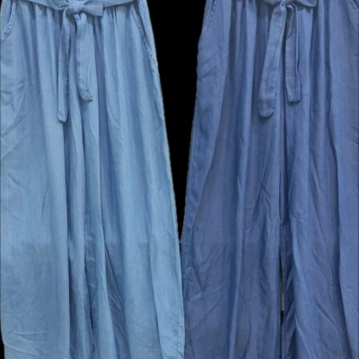 Duas calças azuis largas com cinto, penduradas em cabides pretos