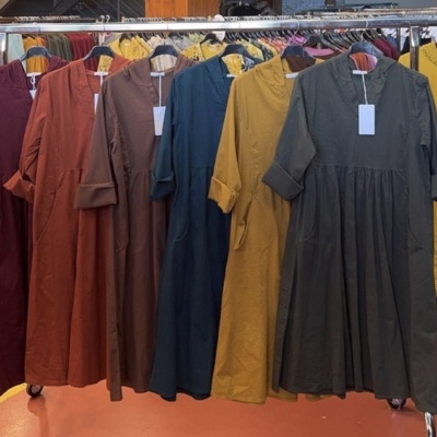 Vestidos compridos com bolsos e capuz em várias cores pendurados num cabide metálico