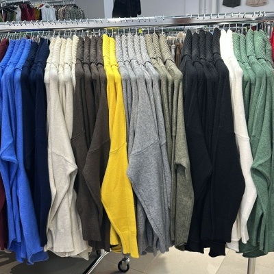 Casacos de malha coloridos pendurados em cabides numa loja de roupa