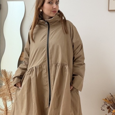 Mulher com casaco comprido bege com fecho preto e botas pretas Hunter em ambiente interior