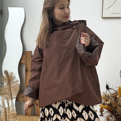 Mulher a usar casaco castanho com vestido padrão geométrico e botas pretas em ambiente interior