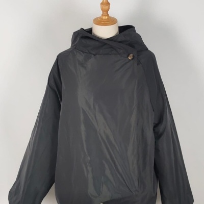 Casaco preto curto com capuz e botão numa apresentação de manequim.