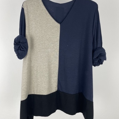 Camisola tricolor cinza, azul escuro e preta com mangas arregaçadas num cabide