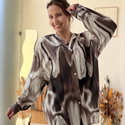Camisa manga comprida castanha marmoreada com botões brancos, mulher sorridente em interior com decoração