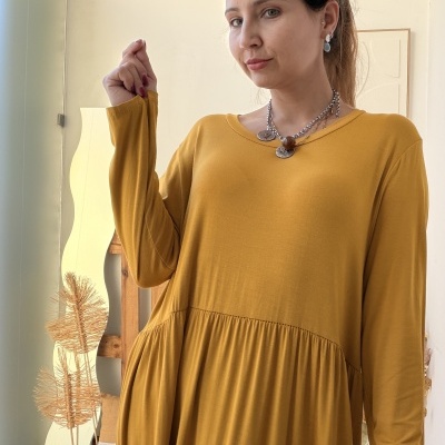 Mulher com vestido amarelo mostarda de manga comprida em ambiente interior