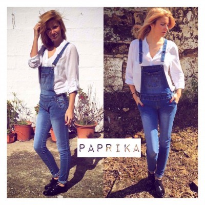 Mulher com camisa branca e jardineiras de ganga azul em ambiente exterior com texto PAPRIKA