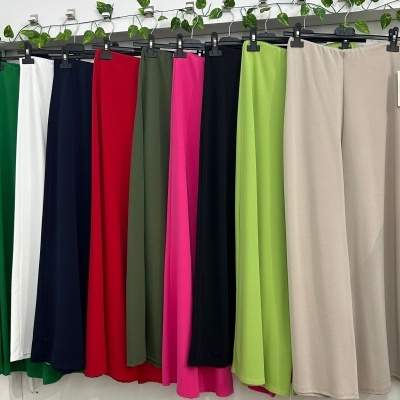 Calças coloridas penduradas em cabides com planta acima