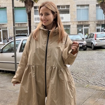 Casaco bege comprido com fecho preto e gola alta usado numa rua