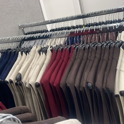 Casacos coloridos pendurados em cabides numa loja de roupa.