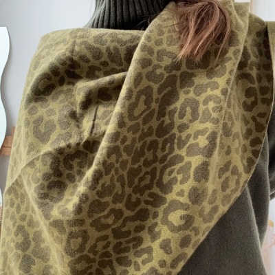 Mulher com cachecol verde de padrão animal e camisola verde-escura