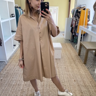 Vestido bege claro de algodão com botões frontais usado numa loja