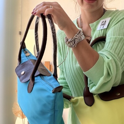 Mulher a segurar malas azul e amarelo com alças castanhas em interior