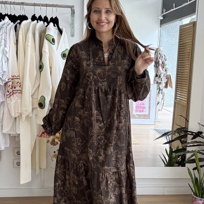 Vestido longo castanho escuro com padrão floral bege e ténis brancos em loja