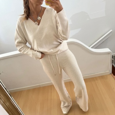 Mulher com conjunto de malha creme em selfie num espelho