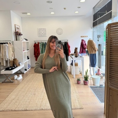 Mulher a usar vestido comprido verde de malha e ténis numa loja de roupa moderna