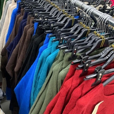 Roupas de malha coloridas penduradas em cabides numa loja