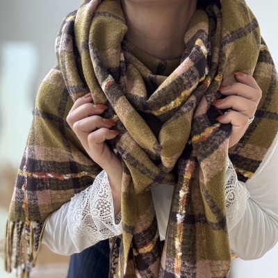 Lenço xadrez felpudo em tons terra usado por mulher com camisa branca e brincos dourados