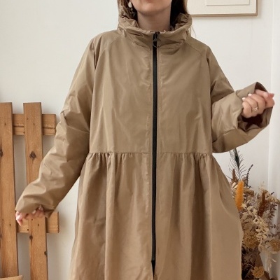 Mulher com casaco bege comprido com fecho preto à frente