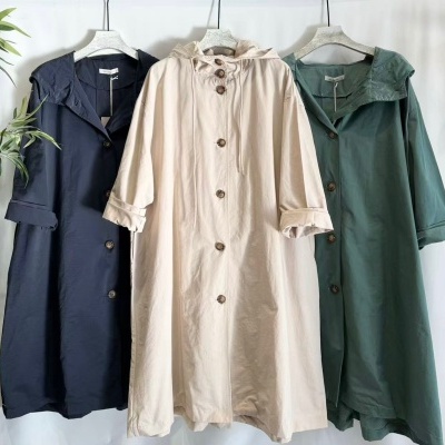 Três casacos compridos com botões e capuz em azul, bege e verde pendurados