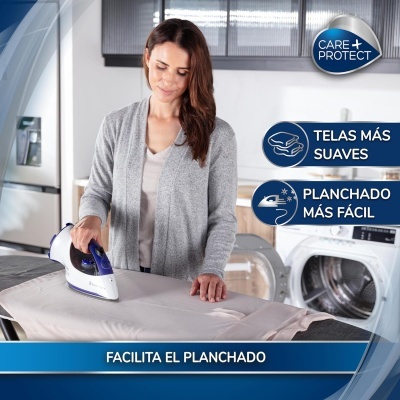 Mulher a passar a ferro roupa bege numa tábua de passar com máquina de lavar ao fundo