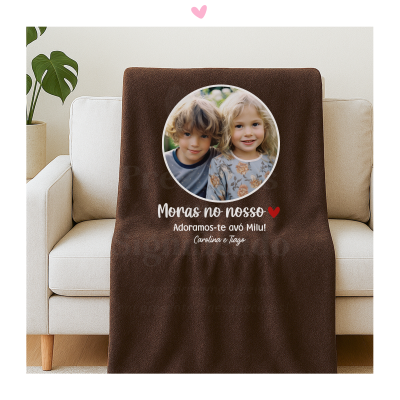 Manta castanha com foto de duas crianças e texto personalizado num sofá bege.