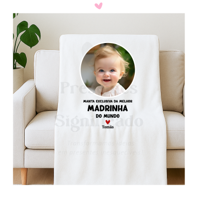 Manta branca com foto de bebé e texto personalizado para madrinha, sobre sofá bege.