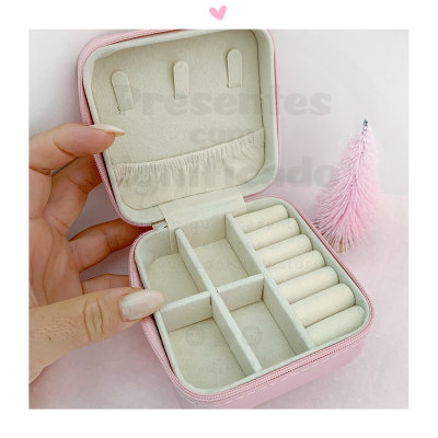 Estojo de joias rosa claro com interior bege e vários compartimentos.