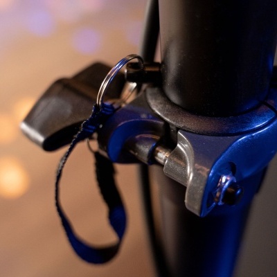 Trava de segurança metálica prateada com cadeado e corda preta numa estrutura preta