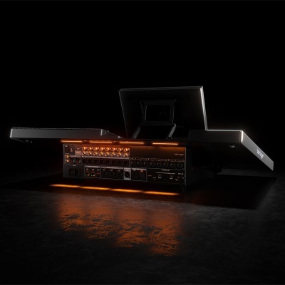 Console de mistura de som preta com botões e ecrã, iluminação laranja