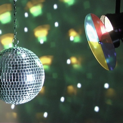 Esfera de discoteca prateada e refletor colorido a projetar luzes numa parede escura