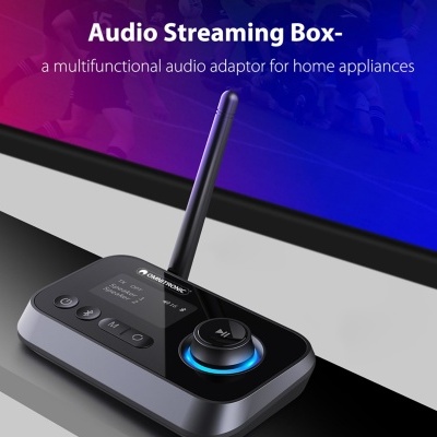 Adaptador de áudio preto com antena e botões diante de ecrã com texto