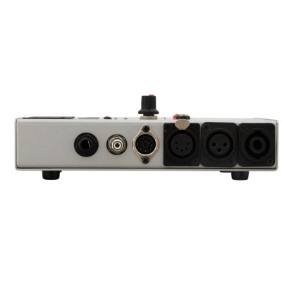 Interface de áudio prateada com várias conexões traseiras colocada sobre superfície branca