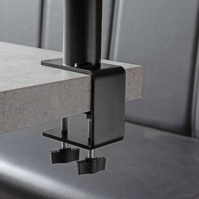 Suporte de metal preto fixado a uma mesa cinza com fundo de estofado preto