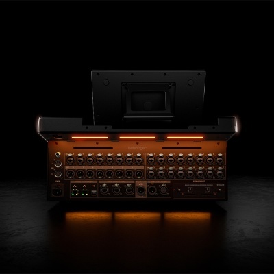 Mesa de mistura Behringer preta com botões e luzes laranja em fundo preto