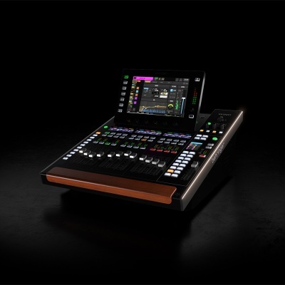 Consola de mistura de áudio digital preta com ecrã tátil e botões coloridos, painel de madeira.