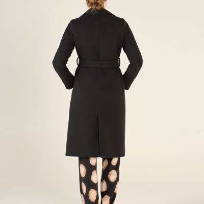 Casaco comprido preto com cinto e calças pretas com manchas bege