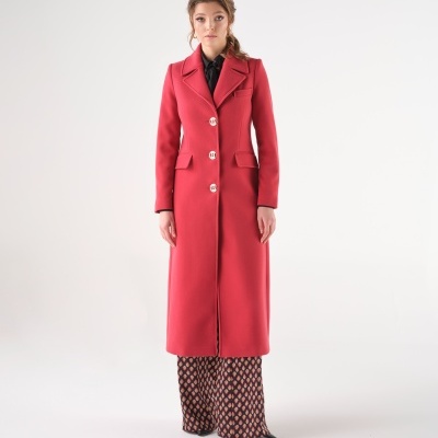 Casaco comprido vermelho com botões e bolsos, calças largas com padrão geométrico